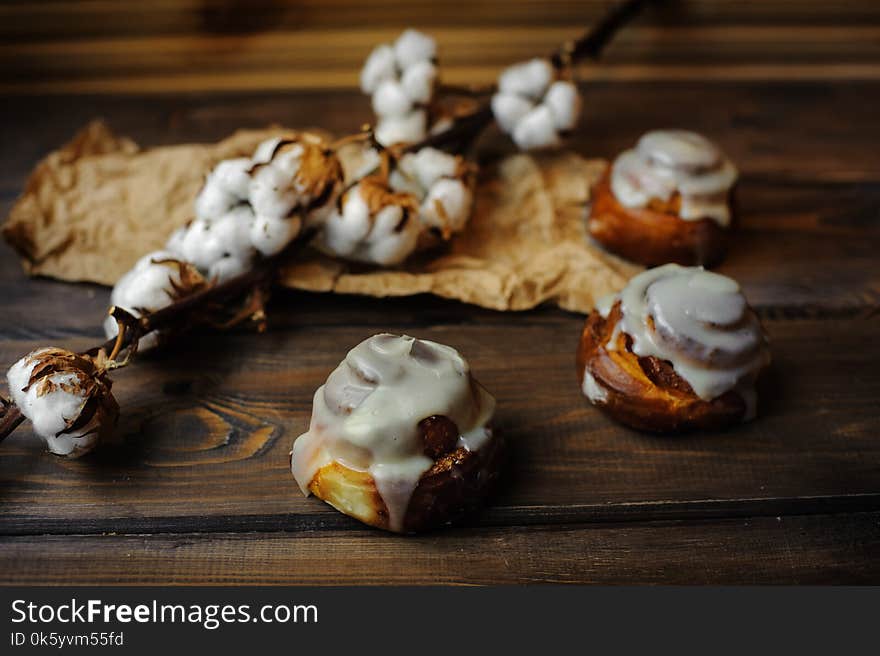 Small buns with custard and cotton flowers decoration on wooden area. Small buns with custard and cotton flowers decoration on wooden area