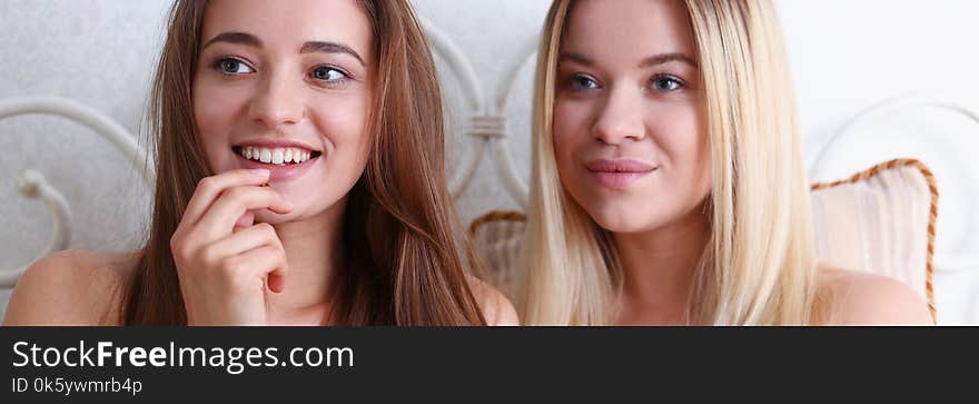 Two happy smiling girlfriends eat popcorn in bed watching TV show early morning holding remote control in hand portrait. Joy cozy tenderness lifestyle football match happiness or tv series concept