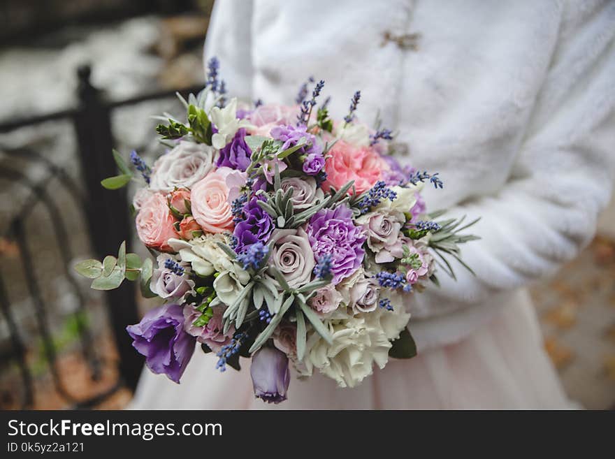 Bride holds wedding bouquet from colorful roses