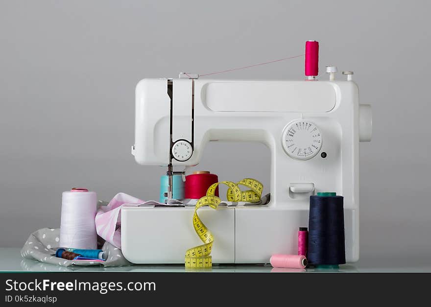 Household electric sewing machine and sewing supplies, on grey background