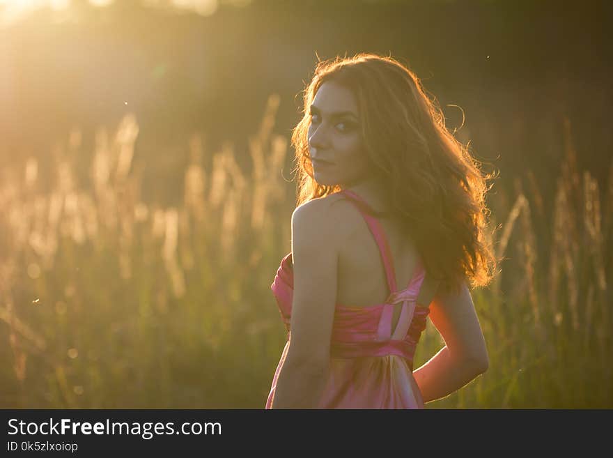 Portrait of a beautiful young woman in meadow at sunset