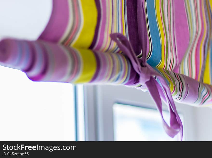 Ornate colourful curtain with lines covering the whole window with bow