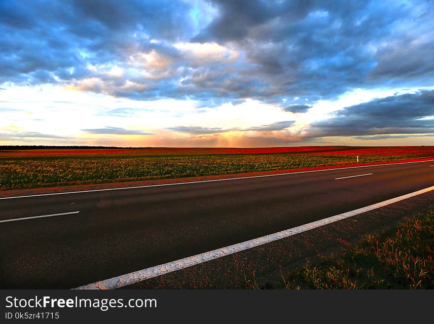 Outgoing road at sunset.Landscape from the outgoing road, fields and sky. Outgoing road at sunset.Landscape from the outgoing road, fields and sky