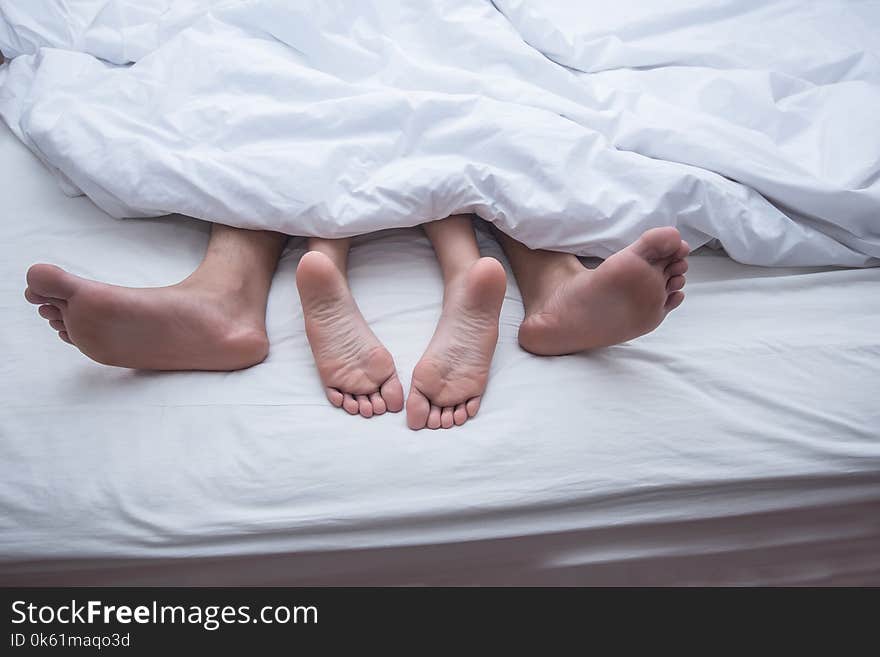 Close up legs of couple in bed.