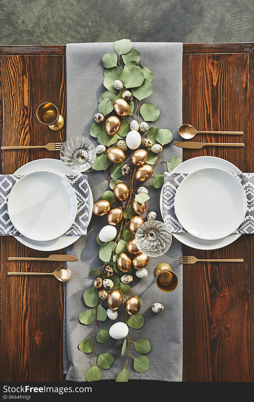 Top view of easter golden eggs, plates and glasses on table in restaurant