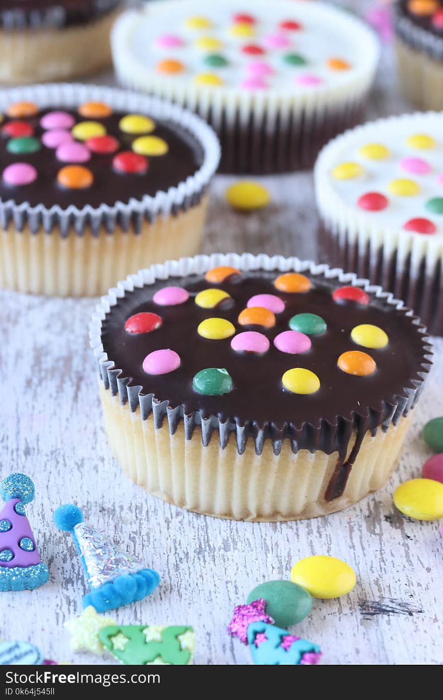 Cupcakes with sugar coated chocolate on a white wooden background