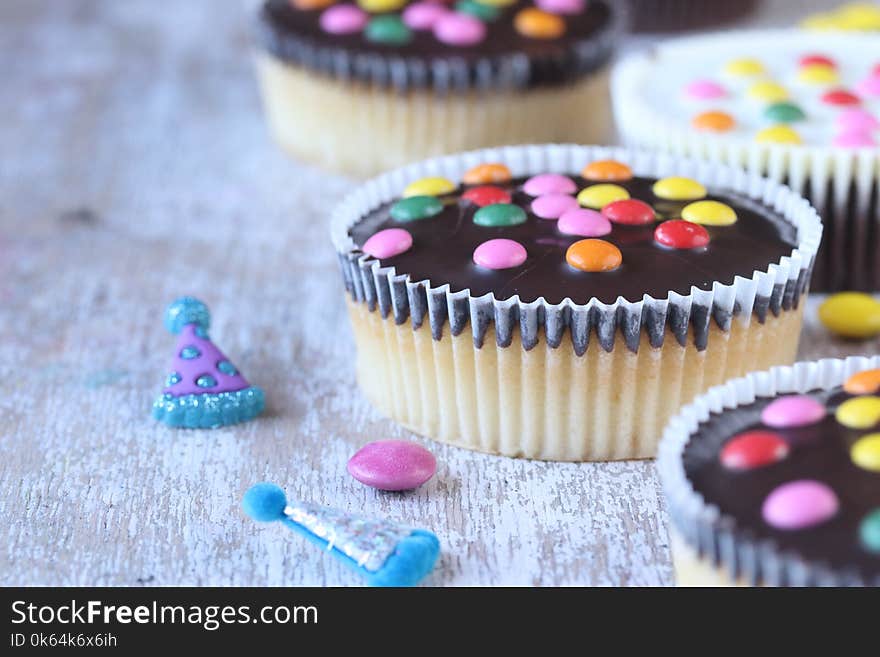 Cupcakes with sugar coated chocolate on a white wooden background