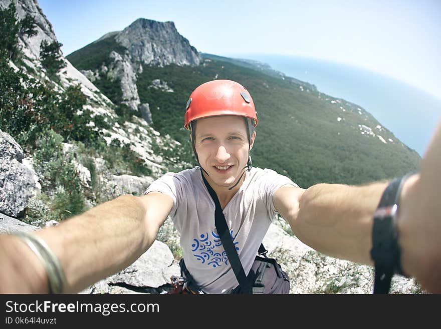 Man climber makes selfie photography with mountains and sea background. Man climber makes selfie photography with mountains and sea background