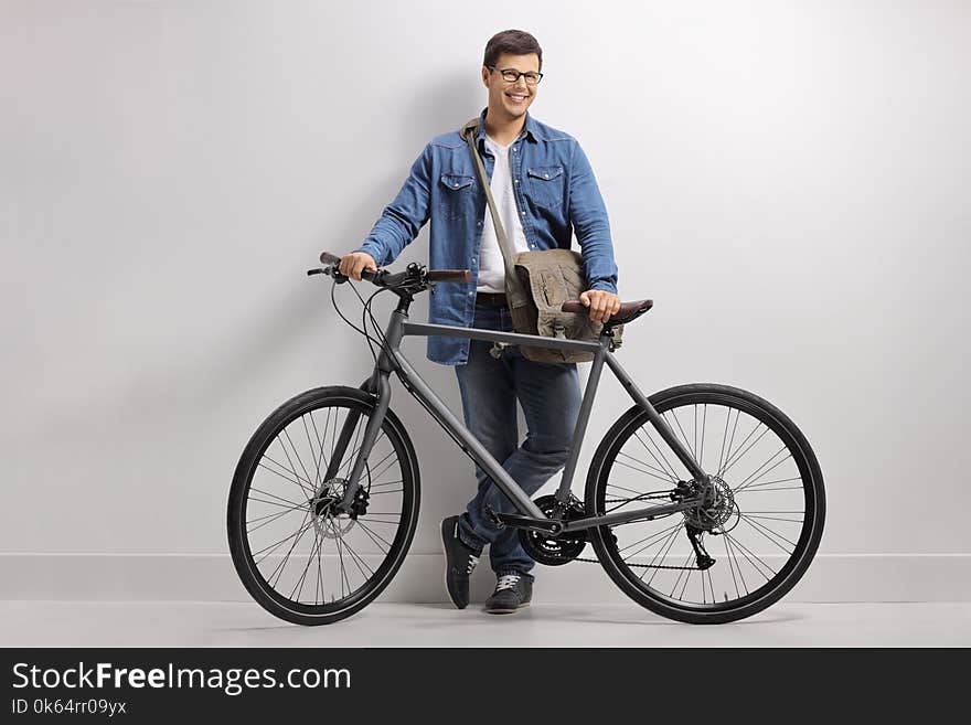 Young Man With A Bicycle Leaning Against A Wall And Smiling