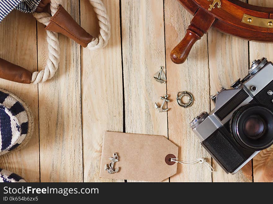 Striped slippers, camera, bag and maritime decorations on the wooden background, top view