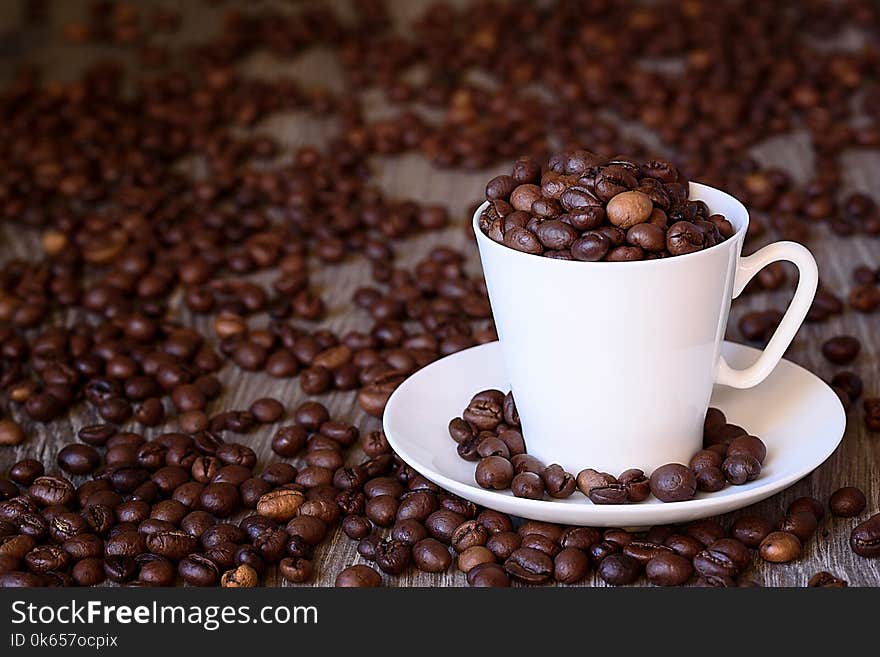 Coffee concept: fried coffee beans in porcelain white coffee cup. Dark background