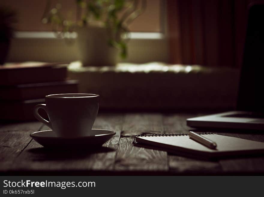 A cup of coffee in the workplace on a wooden table.