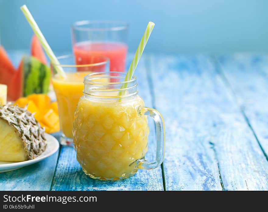 Fresh pineapple and watermelon smoothie in three glasses on a blue wooden rustic background