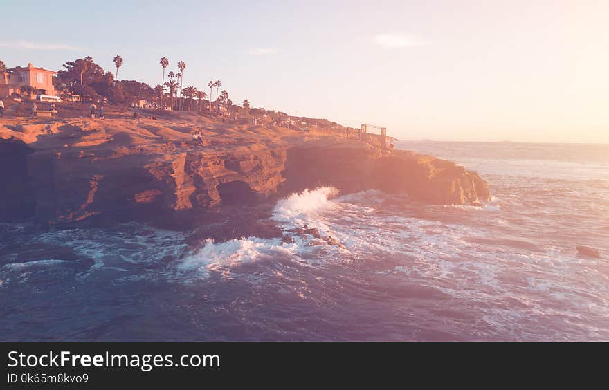 Brown Cliff Beside Ocean Under Blue Sky