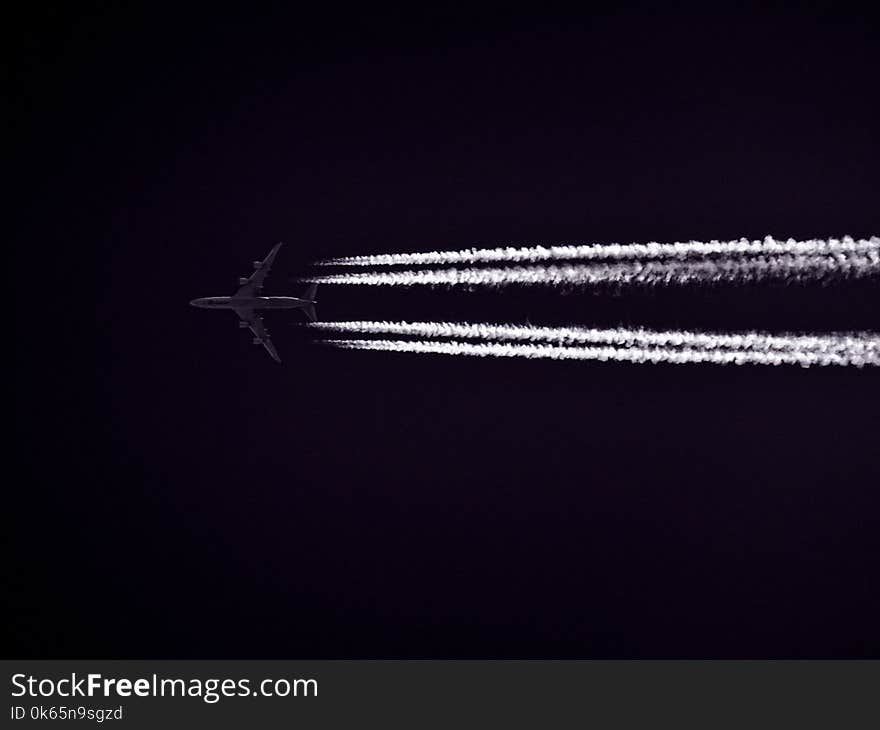 Photo of Airplane Across the Clouds during Night Time