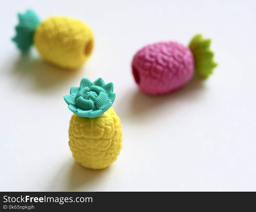 Three Plastic Pineapple Figures on White Surface