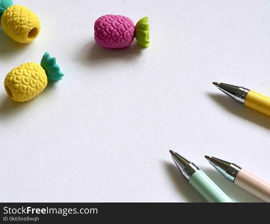 Closeup Photo of Three Assorted-color Pens Near Pineapples Miniatures