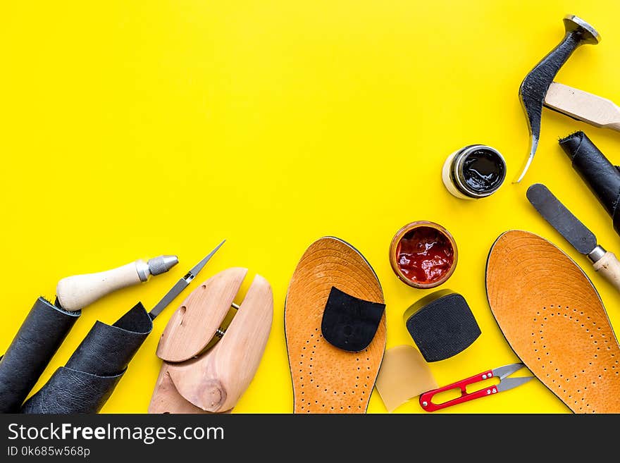 Clobber tools. Hummer, awl, knife, sciccors, wooden shoe, paint and leather. Yellow background top view space for text