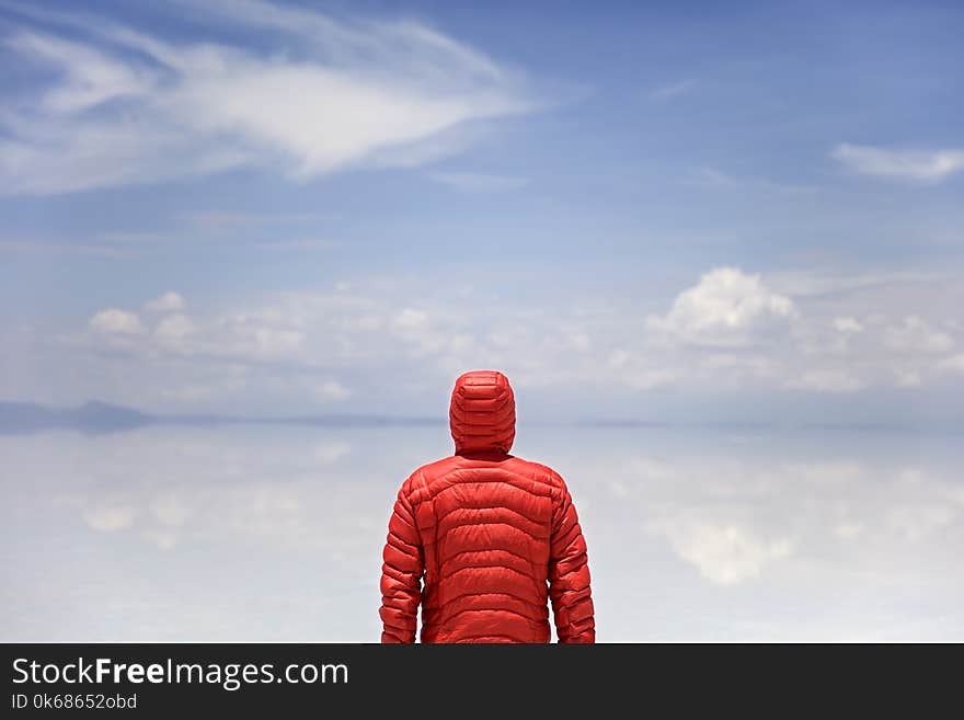 Young man in winter hooded jacket at Salar de uyuni salt flat in Bolivia