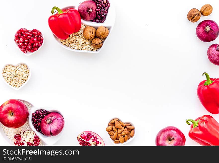 Diet for healthy heart. Food with antioxidants. Vegetables, fruits, nuts in heart shaped bowl on white background top view.