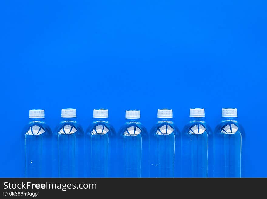 Drinking water in bottles on blue background top view. Drinking water in bottles on blue background top view.