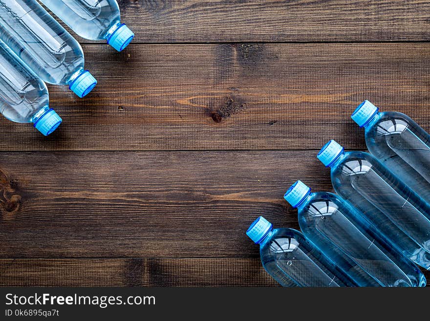 Drinking water in bottles on dark wooden background top view copy space