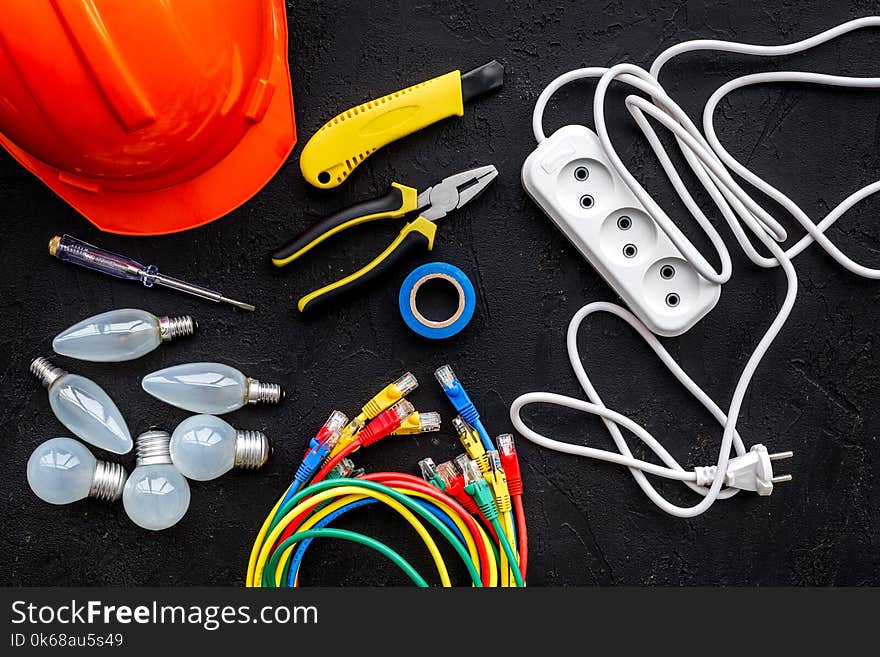 Electrician Work Concept. Hard Hat, Tools, Cabel, Bulb, Socket Outlet On Black Background Top View