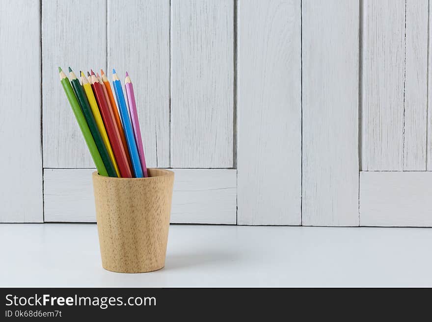 Education workspace background concepts Color Pencil in wooden cup with White wooden vintage wall. back to school concepts