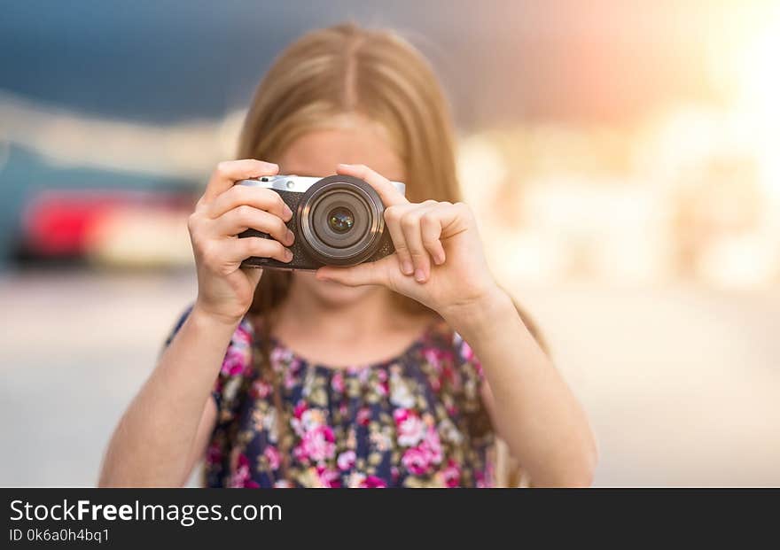 Beautiful little girl with camera takes a picture, summer outdoor