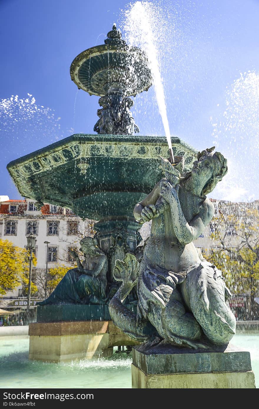 Bronze fountain in baroque style in piazza rossio Lisbon. woman statue in the foreground. Bronze fountain in baroque style in piazza rossio Lisbon. woman statue in the foreground