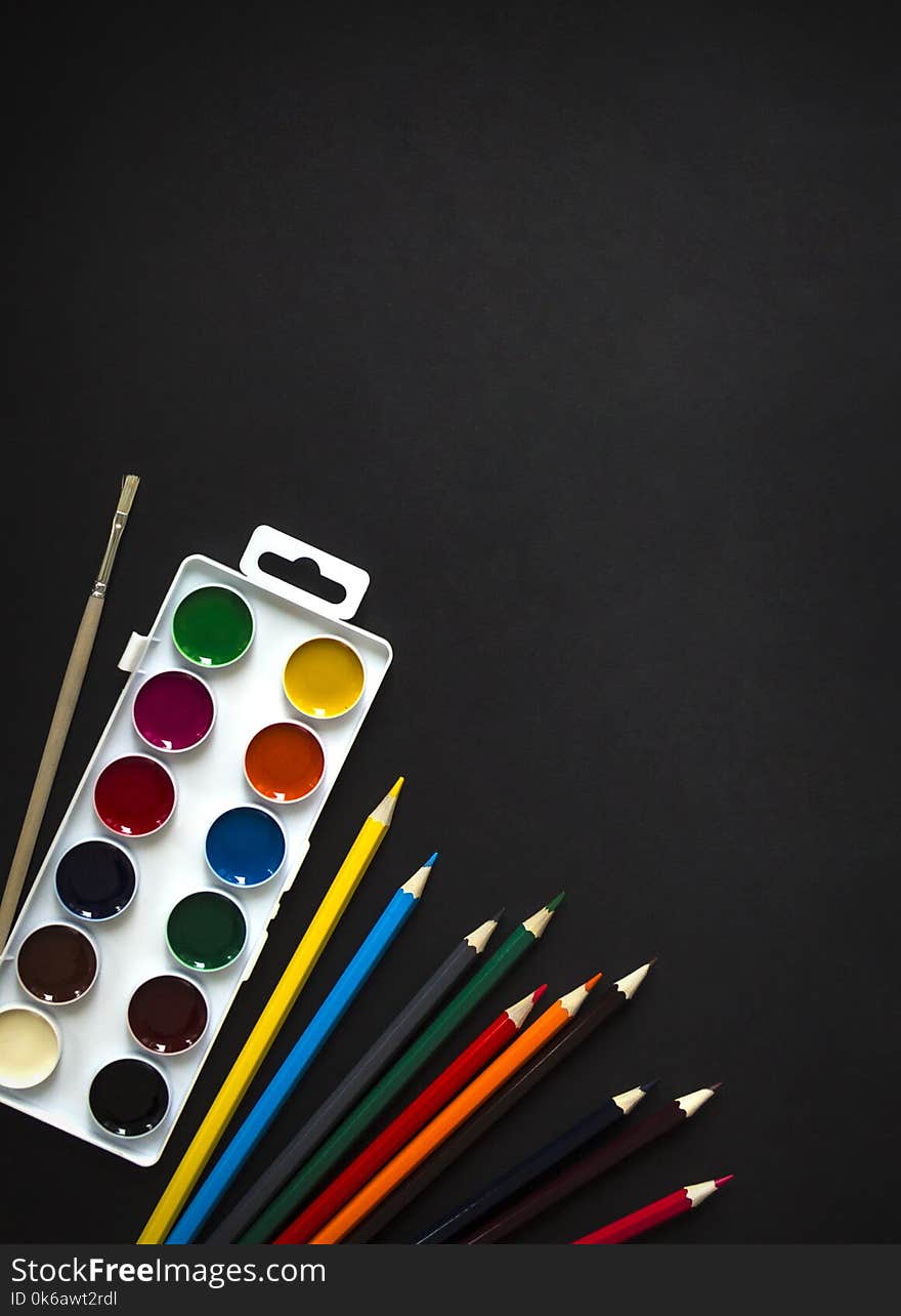 On dark background paint sheet brush pencils colored vertical top view flat lay background knolling