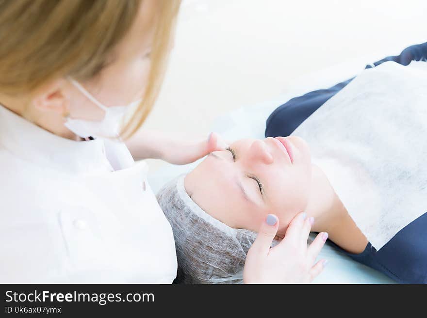 Beauty Saloon. Close-up Of A Medical Beautician In Pink Gloves Makes A Face Massage Of A Beautiful Woman. Cosmetology