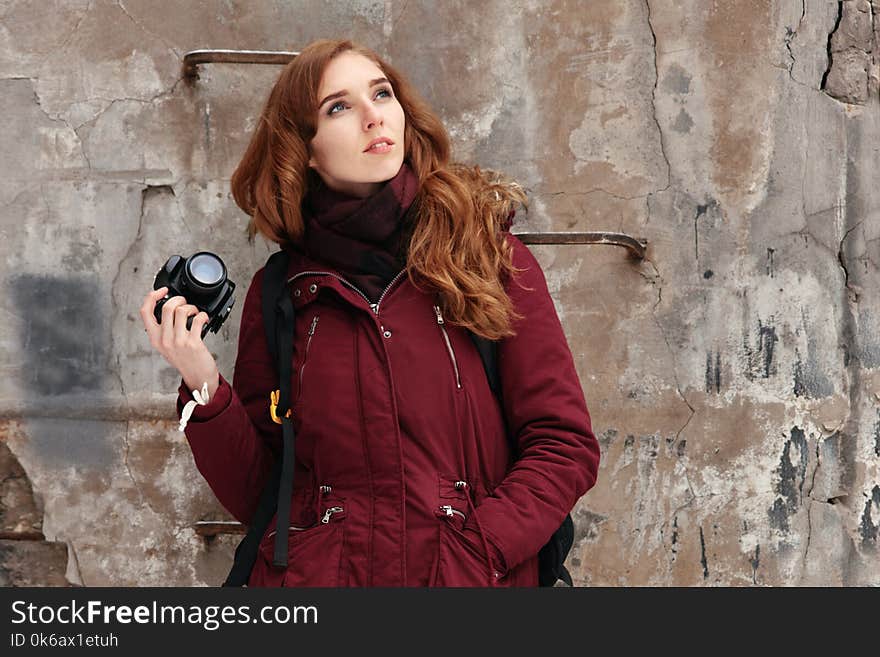 Young red-haired woman with photo camera on outdoor photo session