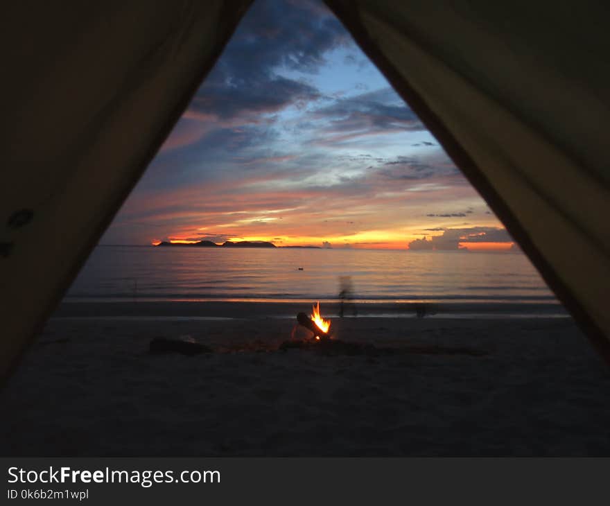 First light of the sunrise from a tent on a beach near Khanom, Thailand. Beach camping. First light of the sunrise from a tent on a beach near Khanom, Thailand. Beach camping.