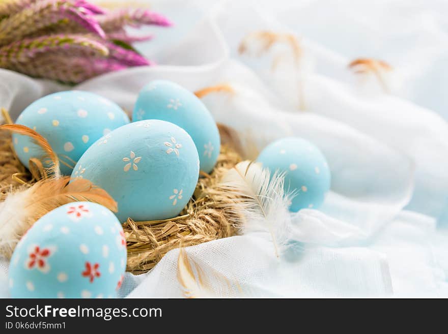 Happy easter! Colorful of Easter eggs in nest with flower, paper star and Feather on white cheesecloth background.