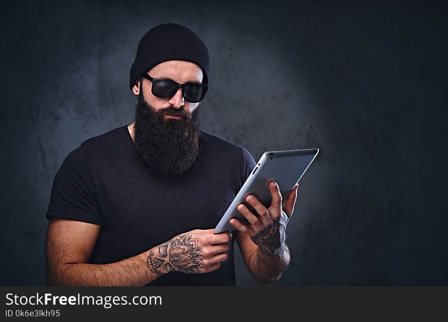 A man in a hat and sunglasses holds tablet PC.