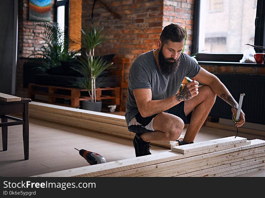 Carpenter measuring boards in a room with loft interior.