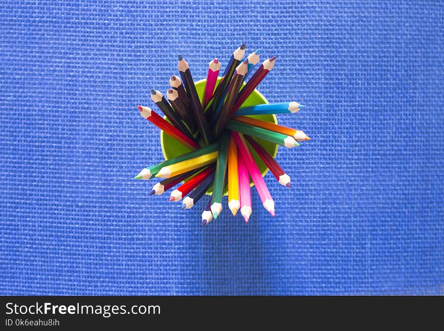 Set Of Colored Pencils In A Glass On A Blue Background