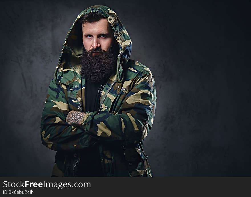 Urban Look Bearded Male With Crossed Arms Dressed In A Camouflage Jacket.