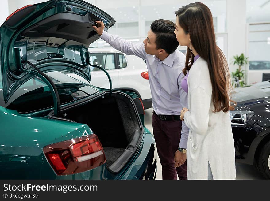 Vietnamese married couple checking trunk closing mechanism. Vietnamese married couple checking trunk closing mechanism