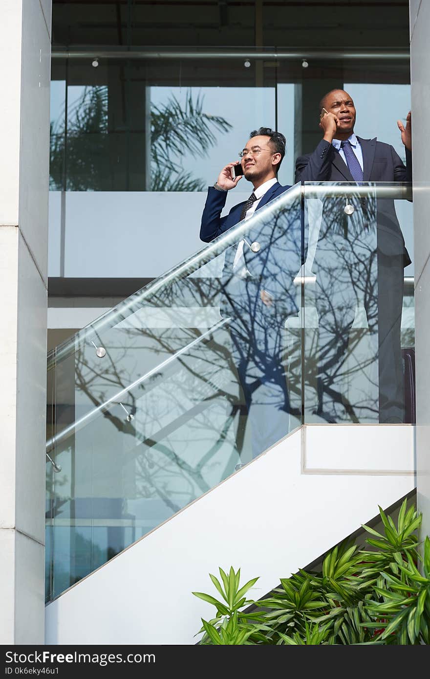 Business executives standing on stairs and talking on the phone. Business executives standing on stairs and talking on the phone