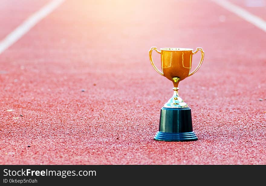 Gold trophy on red Track in stadium ,leadership ;success in business concept