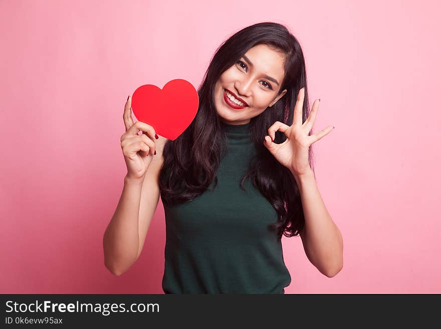 Asian woman show OK with red heart on pink background. Asian woman show OK with red heart on pink background