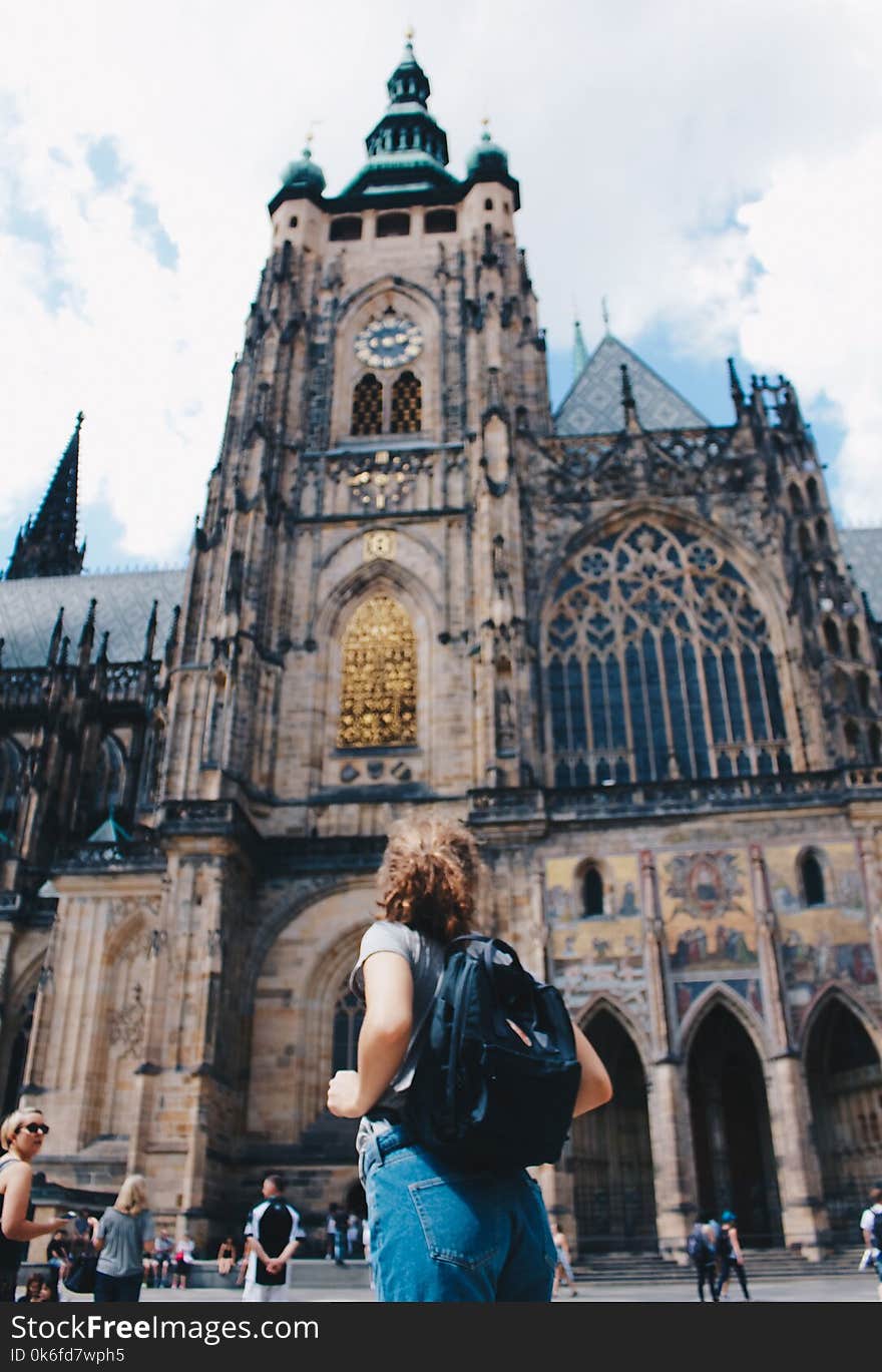 Woman Wearing Backpack And Grey Shirt Near Brown Church