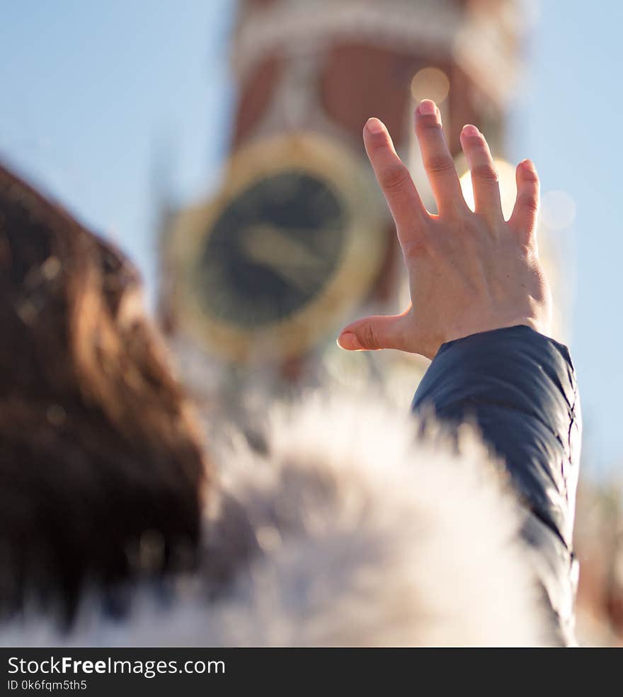 The girl touches the clock in Moscow with her hand .