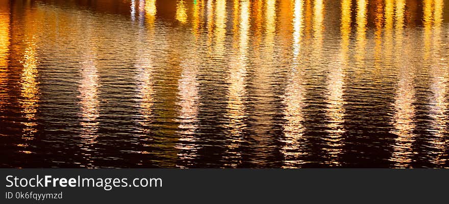 Light of lanterns on the smooth surface of water at night as a background