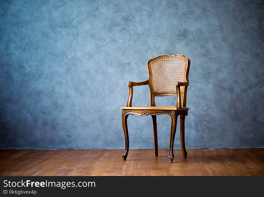 Old chair on a gray wall background.