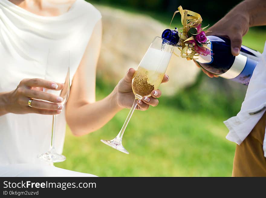 Man pours champagne into glasses which holds woman. Man pours champagne into glasses which holds woman