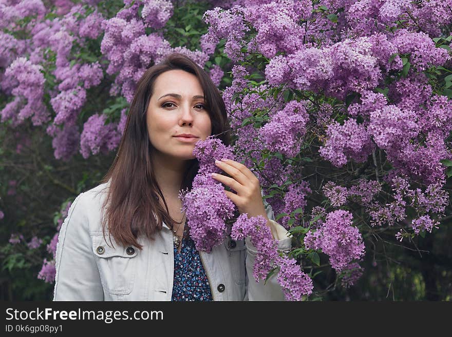 Beautiful woman and blooming lilac in the garden. Female