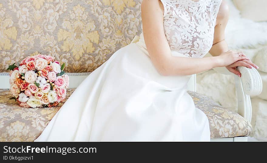 Bridal bouquet lies on a bench near a bride indoor closeup